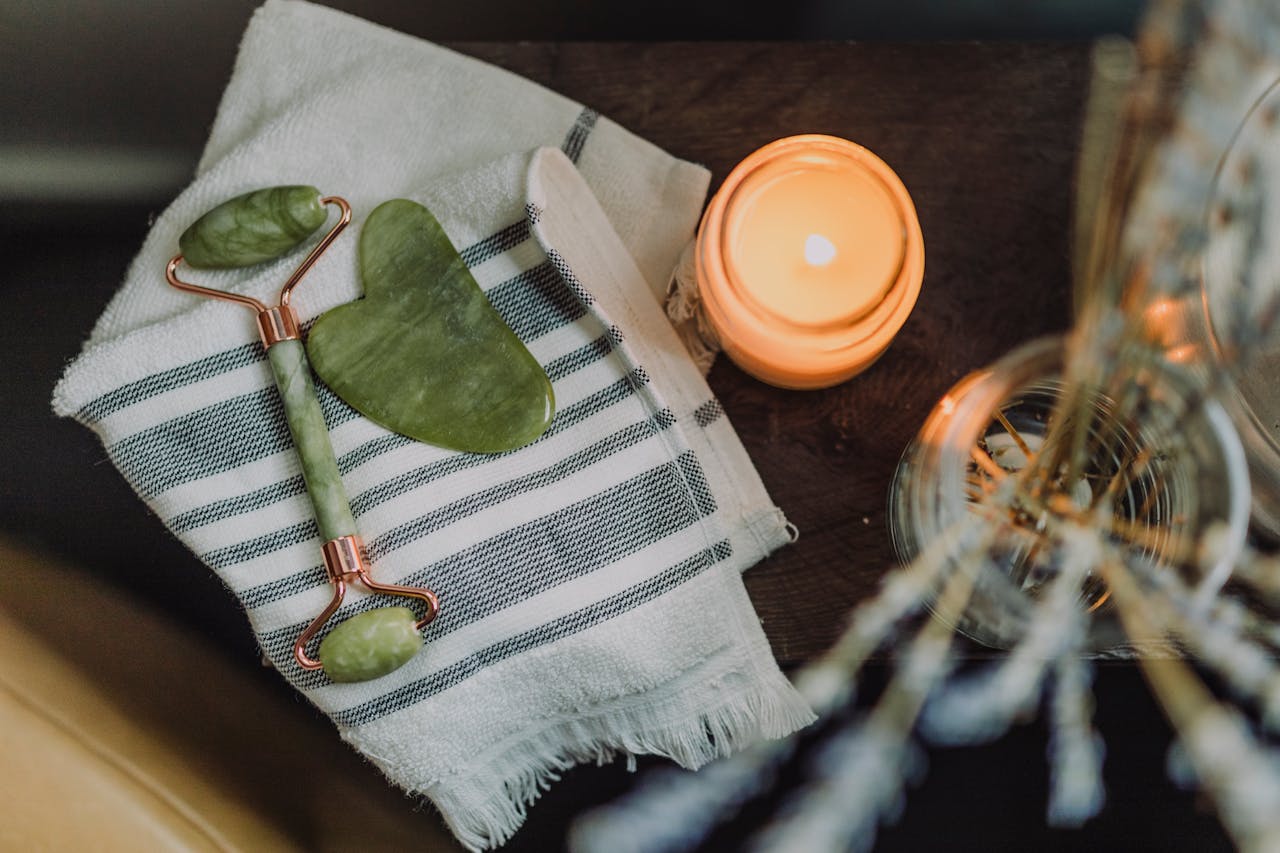 why-choose-us A serene spa setup featuring a jade roller, gua sha, towel, and candle for ultimate relaxation.