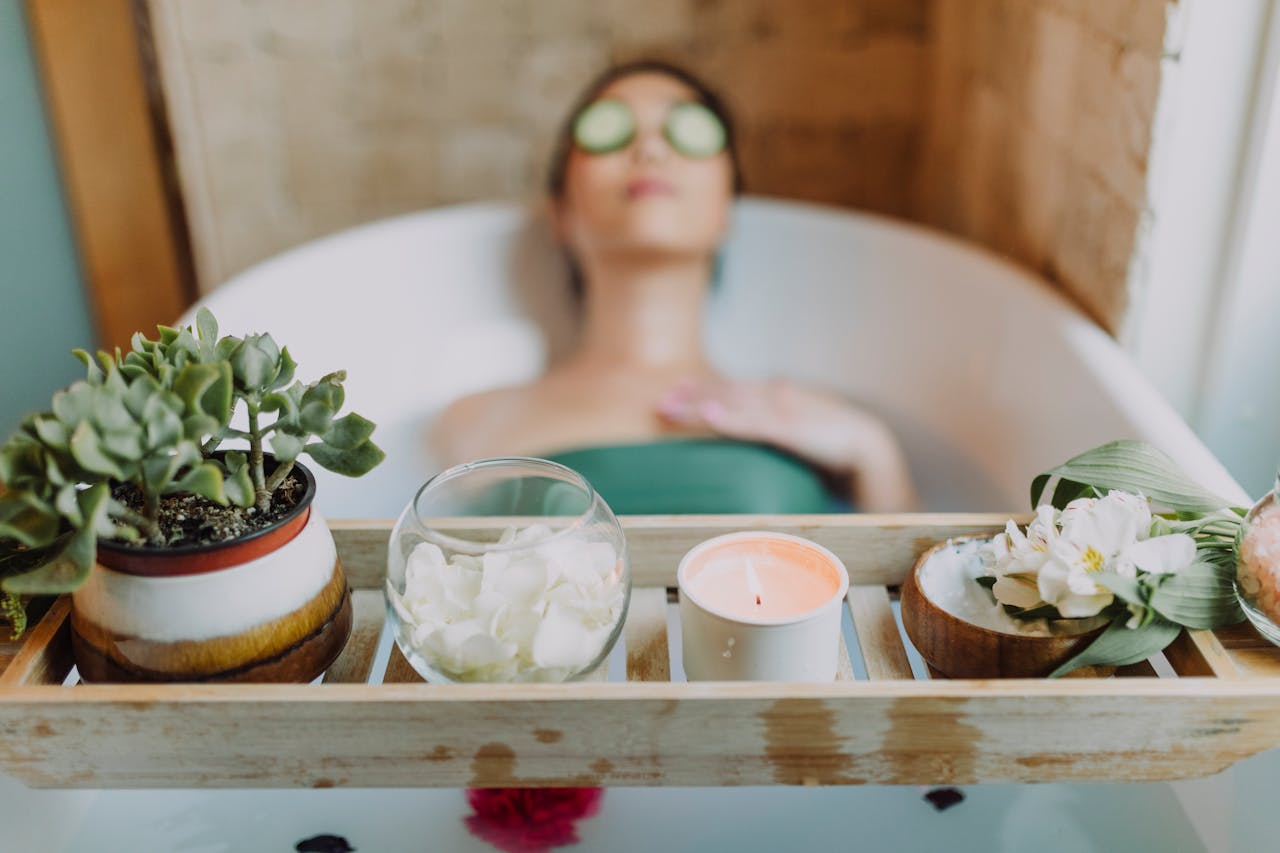 get-in-touch Woman relaxing in a bathtub with a candle and plants, enjoying a serene spa experience.